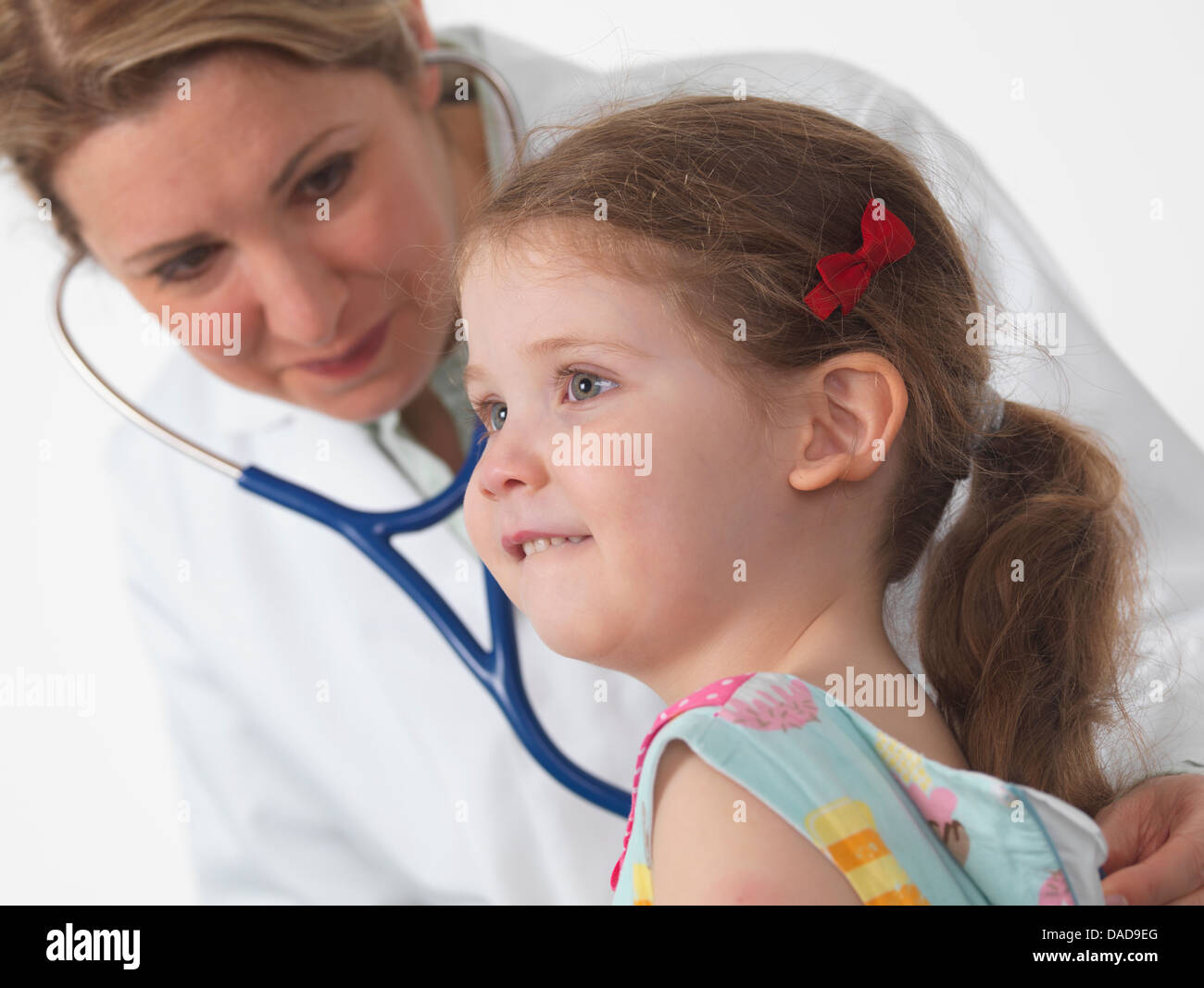 Paediatric doctor listening for heart and lungs of a small girl in surgery Stock Photo