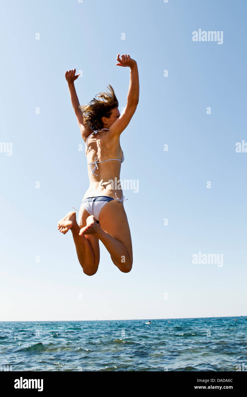 Woman jumping into sea Stock Photo