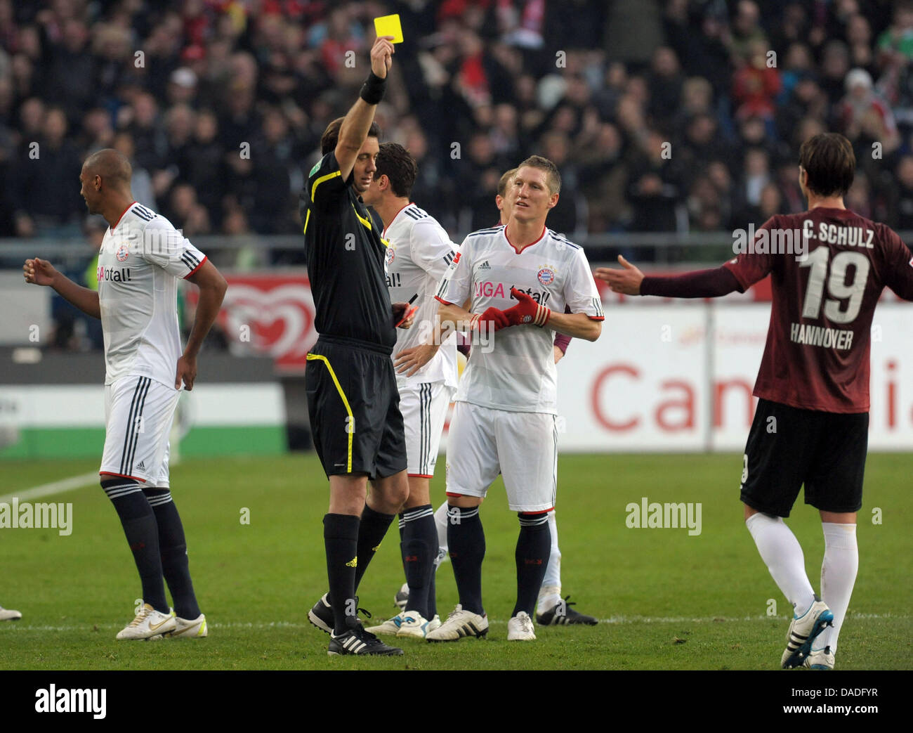 Referee Manuel Graefe shows a yellow card to Hanover's Christian Schulz (R) during the German Bundesliga soccer match between Hanover 96 and Bayern Munich at the AWD Arena in Hanover, Germany, 23 October 2011. Photo: PETER STEFFEN Stock Photo