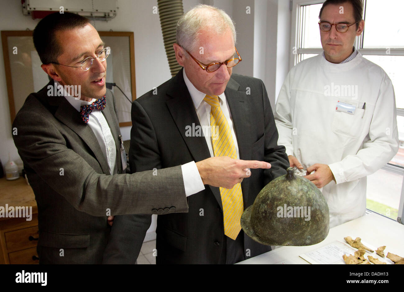 Chief archaeologists of the of the Regional authority association of Westphalia-Lippe (LWL), Michael Rind (L-R), LWL-Director Wolfgang Kirsch and head of the restoration department Sebastian Pechtold present a military helmet, found in the Muenster region near Olfen, in the rooms of the LWL in Muenster, Germany, 25 October 2011. 2,000-year-old findings from a Roman military camp ha Stock Photo