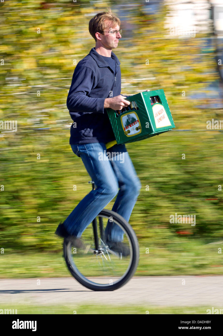 Martin Eisenreich carries a beer crate while riding his unicycle through Ilmenau, Germany, 24 October 2011. The student uses his unicycle for most of his errands. He takes his bicycle only when he is in a hurry. Photo: Michael Reichel Stock Photo
