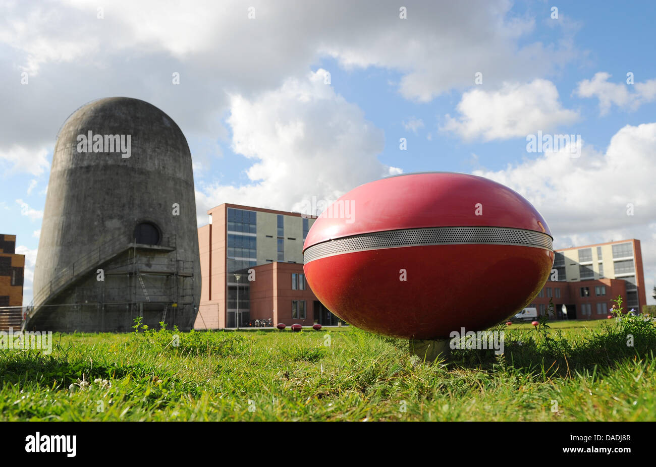 A red elliptical object that is a part of the sound installation AIR BORNE is situated in front of the Trudelturm (L) at the Aerodynamic Park on campus of the Humboldt University of Berlin in Berlin-Adlershof, Germany, 13 October 2011. The trudelturm was erected for scientific purposes in the 1930's and is a monument today, that shall reminds visitors of the history of the specific Stock Photo