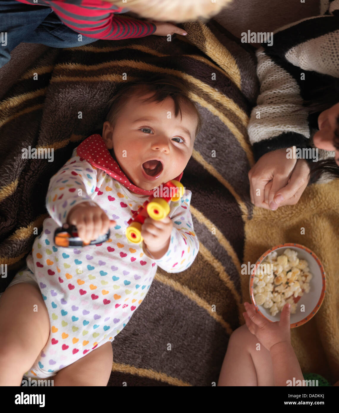 Baby holding toys and lying on back, overhead view Stock Photo