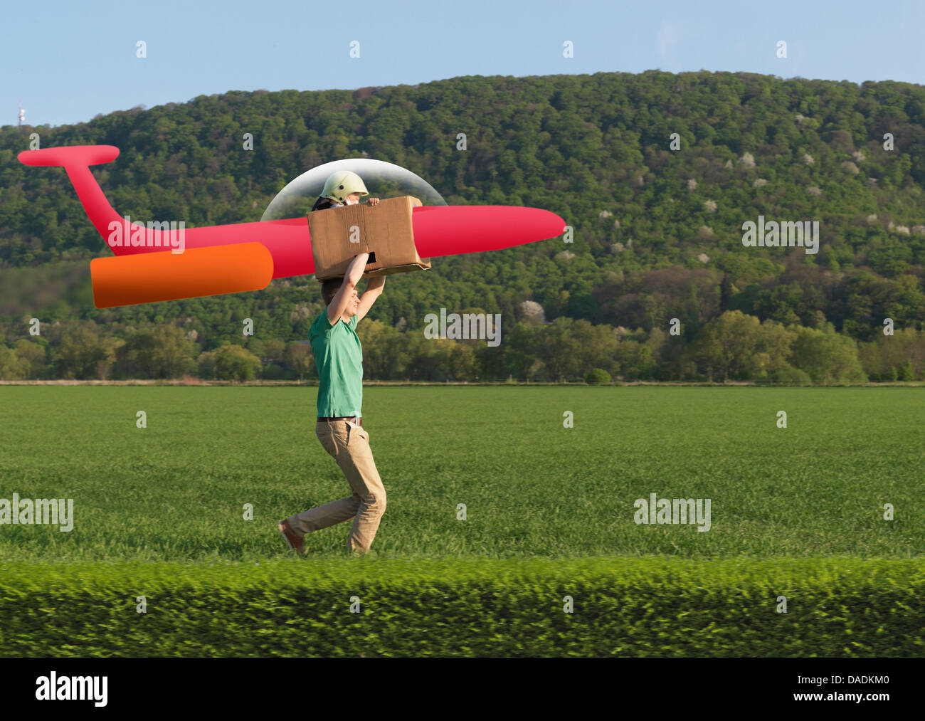 Man running with child in model airplane across field Stock Photo