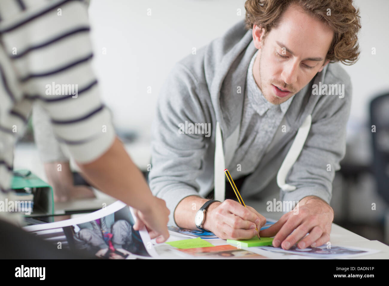 Young man making notes on desk in creative office Stock Photo
