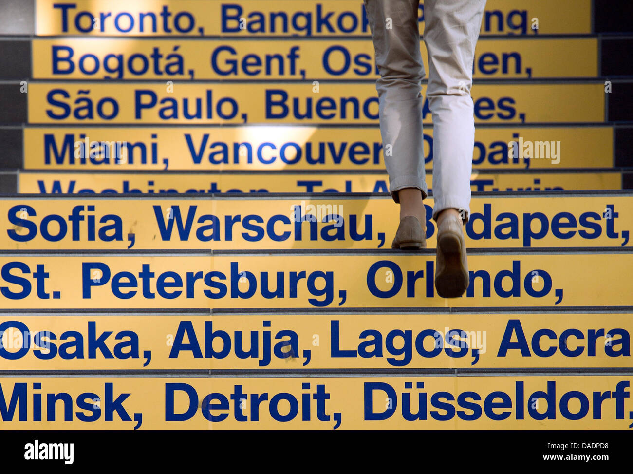 A woman ascends steps with the names of global cities inside the airport in Dresden, Germany, 01 November 2011. Photo: Arno Burgi Stock Photo