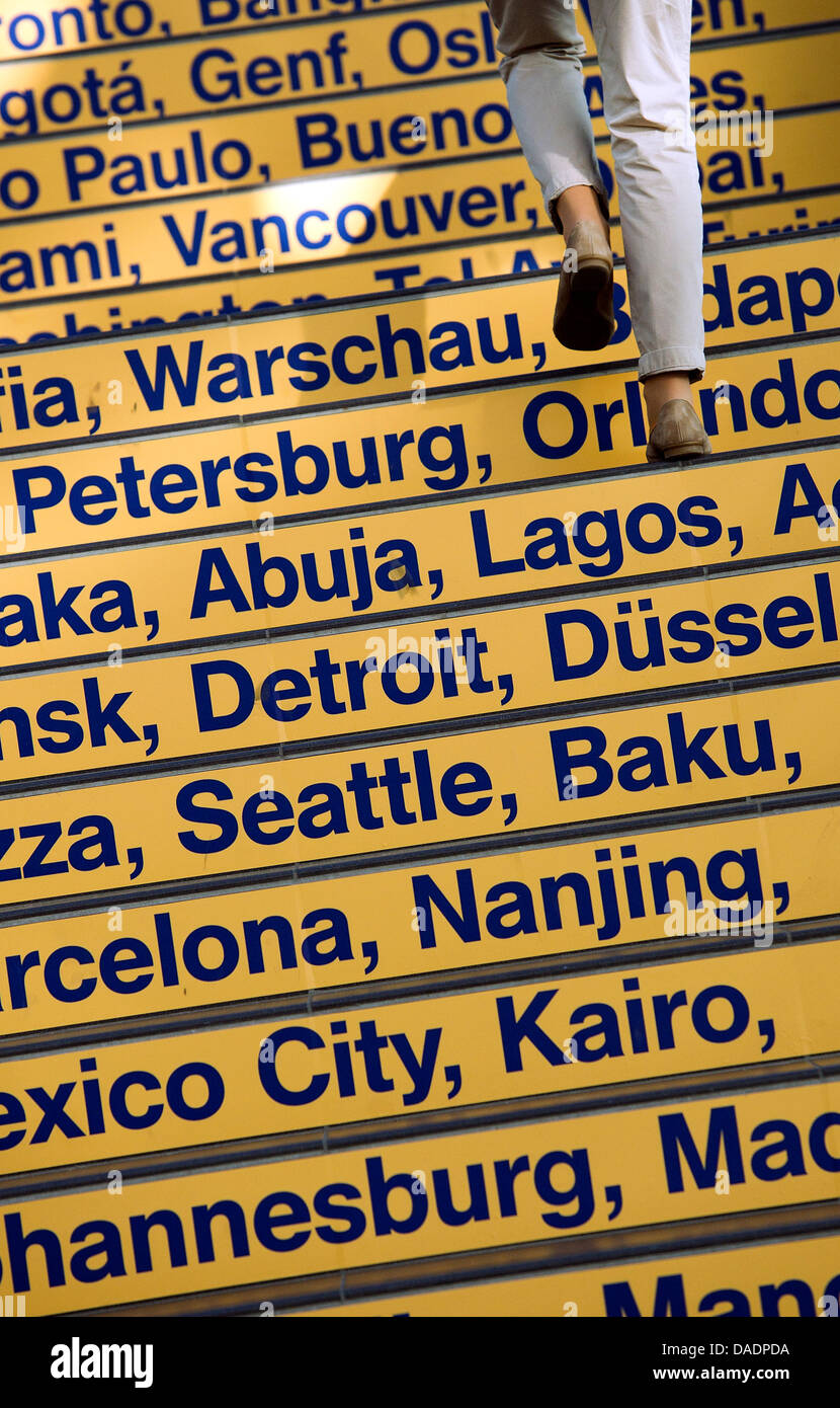 A woman ascends steps with the names of global cities inside the airport in Dresden, Germany, 01 November 2011. Photo: Arno Burgi Stock Photo