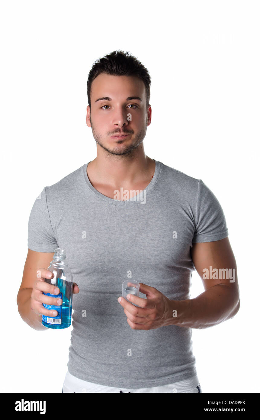 Handsome young man using mouthwash to clean his teeth and mouth, isolated on white background Stock Photo