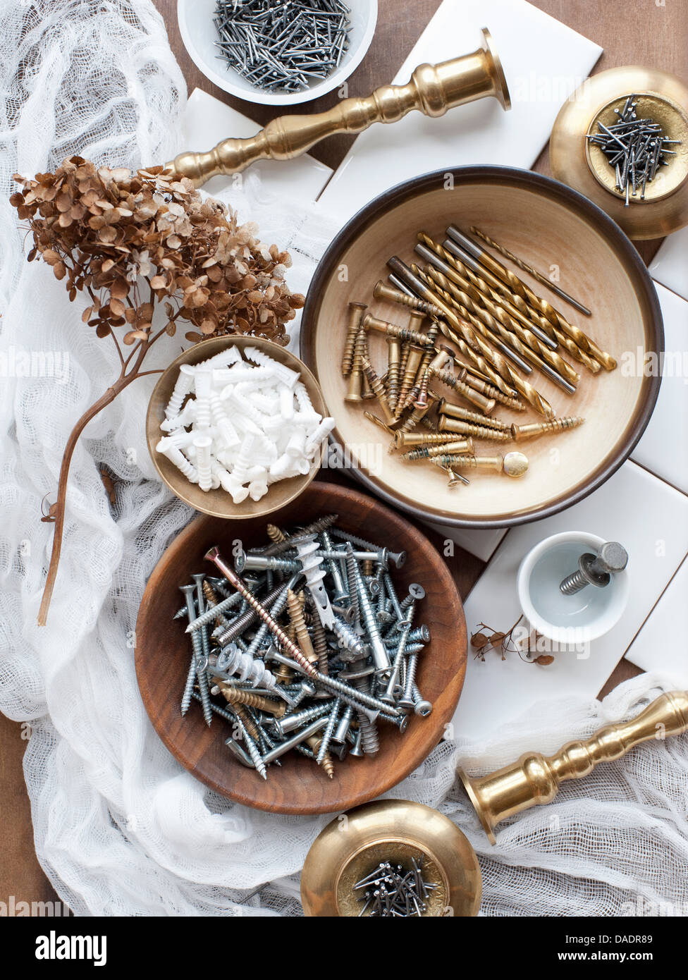 Still life of screws, nails and brass candlesticks Stock Photo