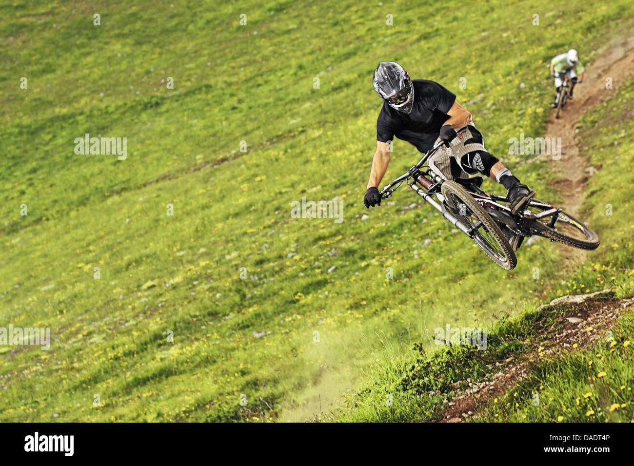 Mountain bikers riding down steep grassy slope Stock Photo Alamy
