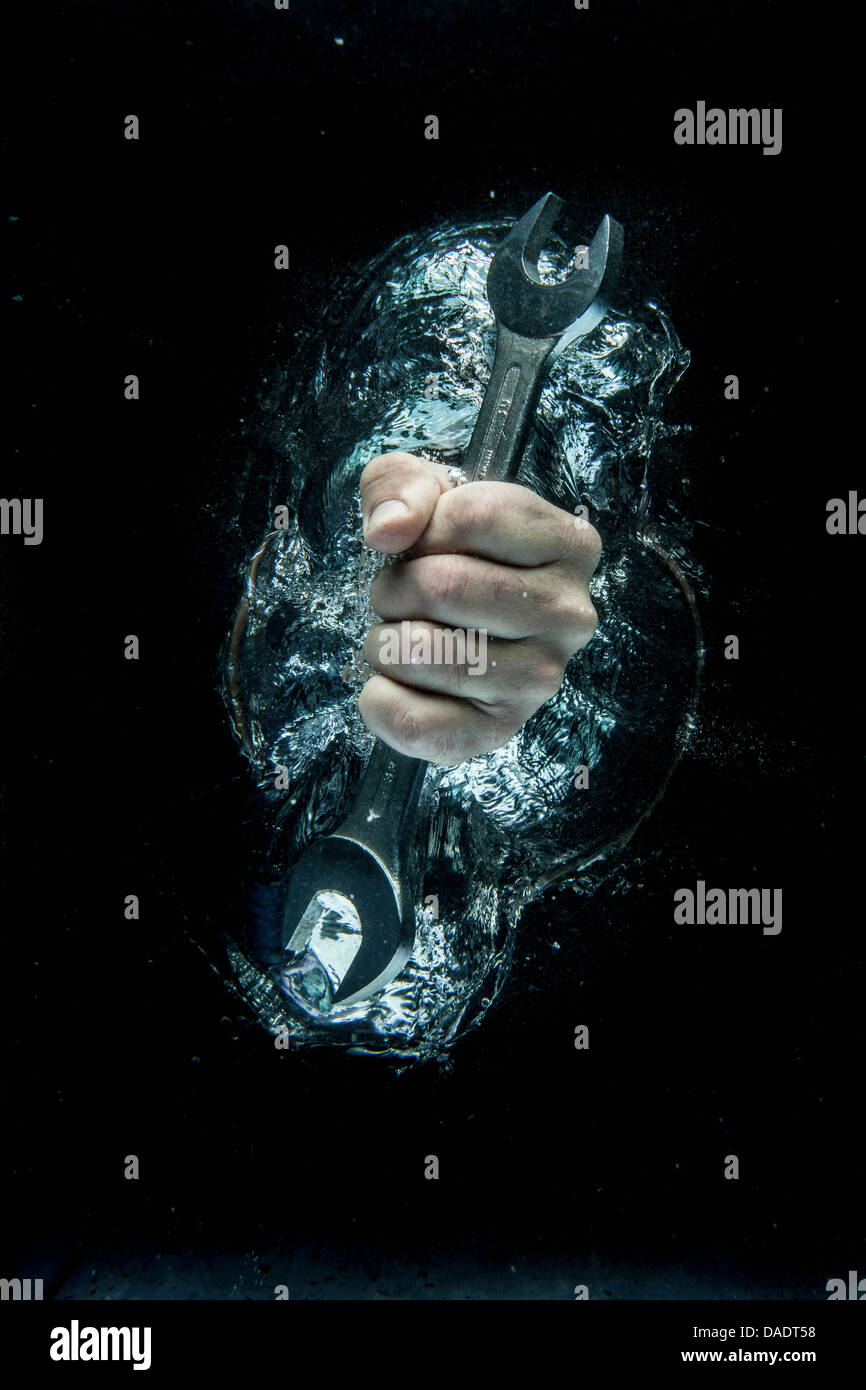 Male hand gripping wrench beneath water Stock Photo