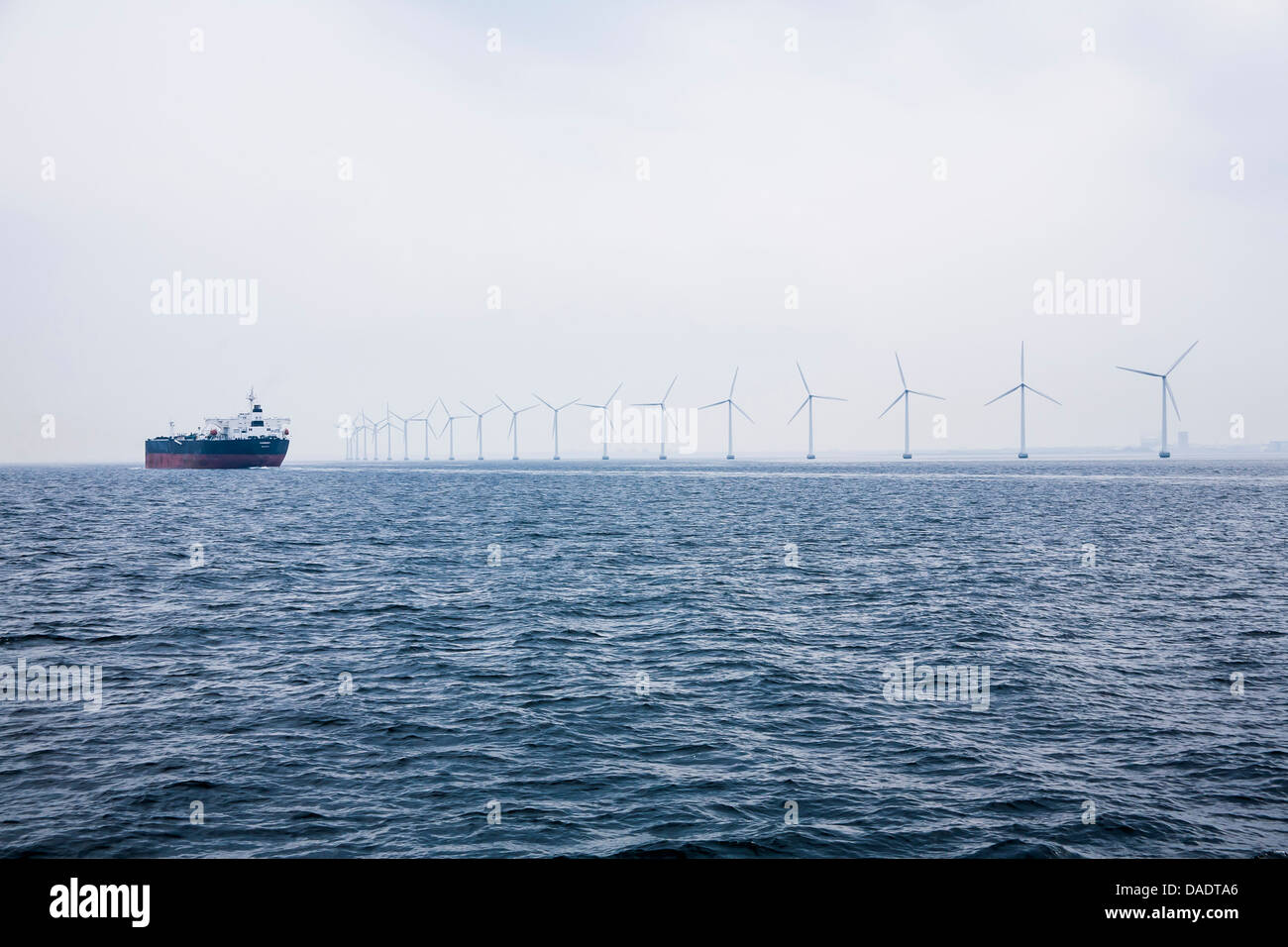 Germany, Hamburg, View of cargo ship in front of the wind-wheels of an offshore windpark Stock Photo