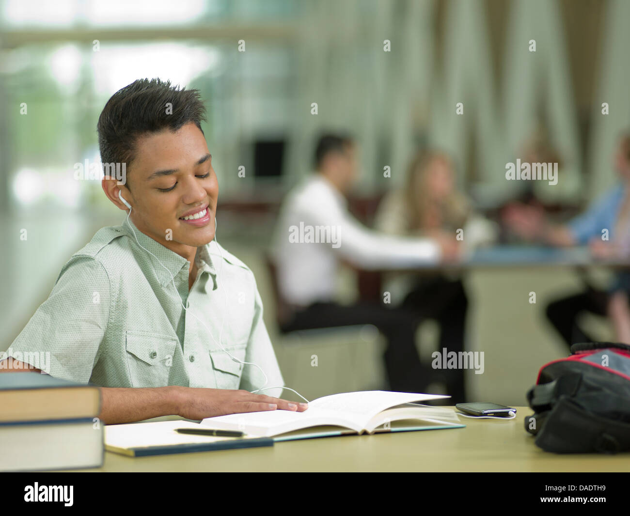 Young student wearing earphones and looking at school books Stock Photo