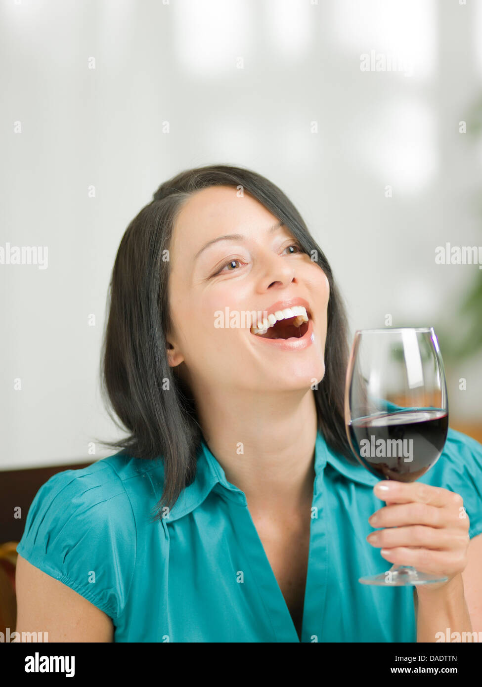 Mature woman holding glass of wine and laughing Stock Photo - Alamy
