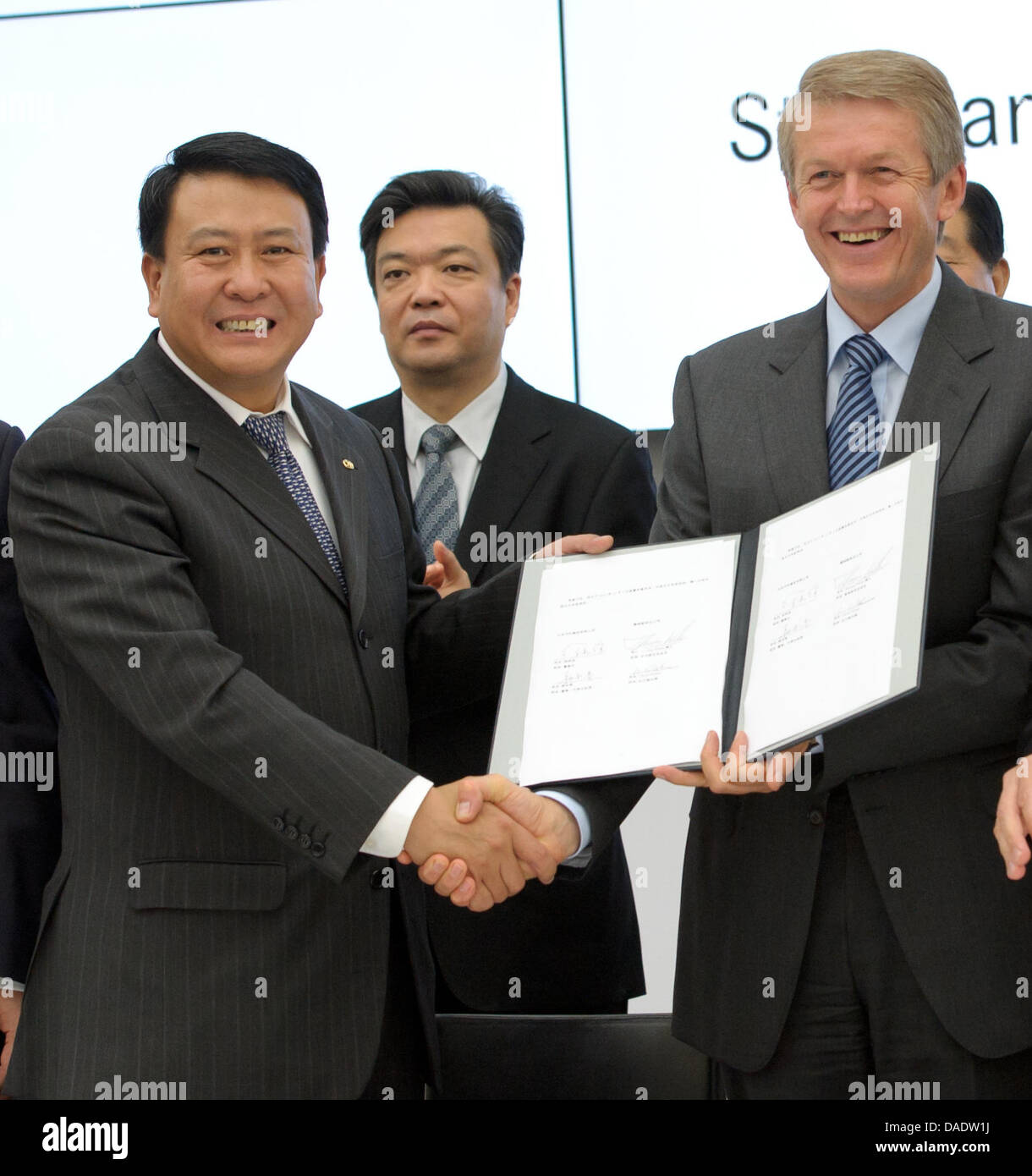 Chairman of Chinese car manufacturer BAIC, Xu Heyi (L), and research and development chairman of Daimler and Mercedes Benz Cars, Thomas Weber (R), shake hands after signing  a declaration of intent between Daimler and BAIC in a Daimler factory in Sindelfingen, Germany, 02 November 2011. Deputy Mayor of Bejing, Ji Lin (C) claps hands. The car manufacturer Daimler and the Chinese par Stock Photo
