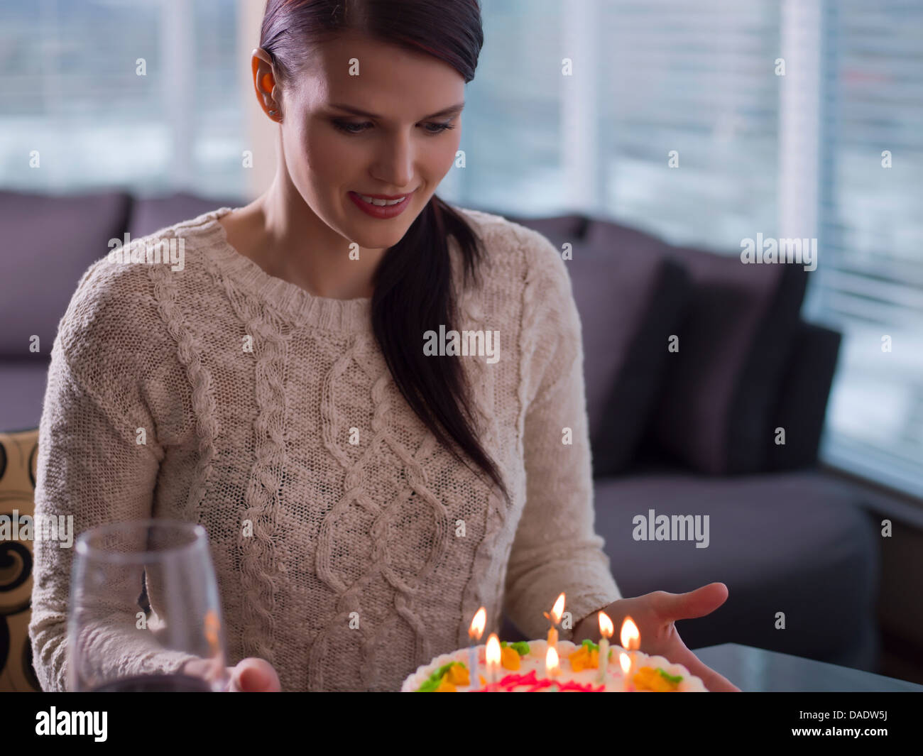 Young woman looking at birthday cake Stock Photo
