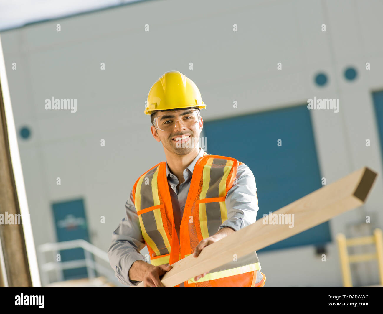 Mid adult construction worker holding wood Stock Photo