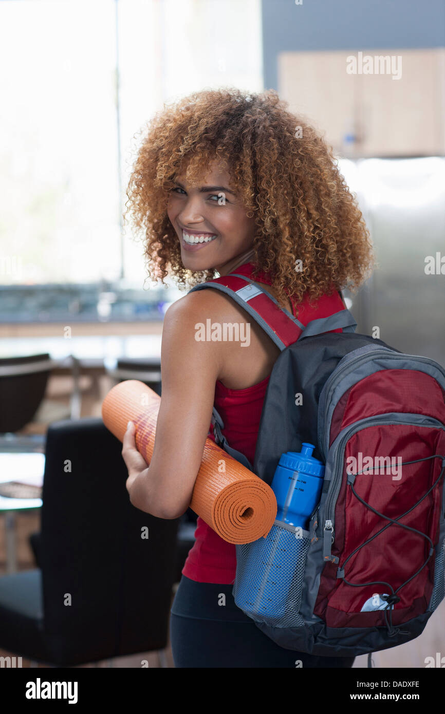 Mid adult woman in carrying yoga mat and rucksack, portrait Stock Photo