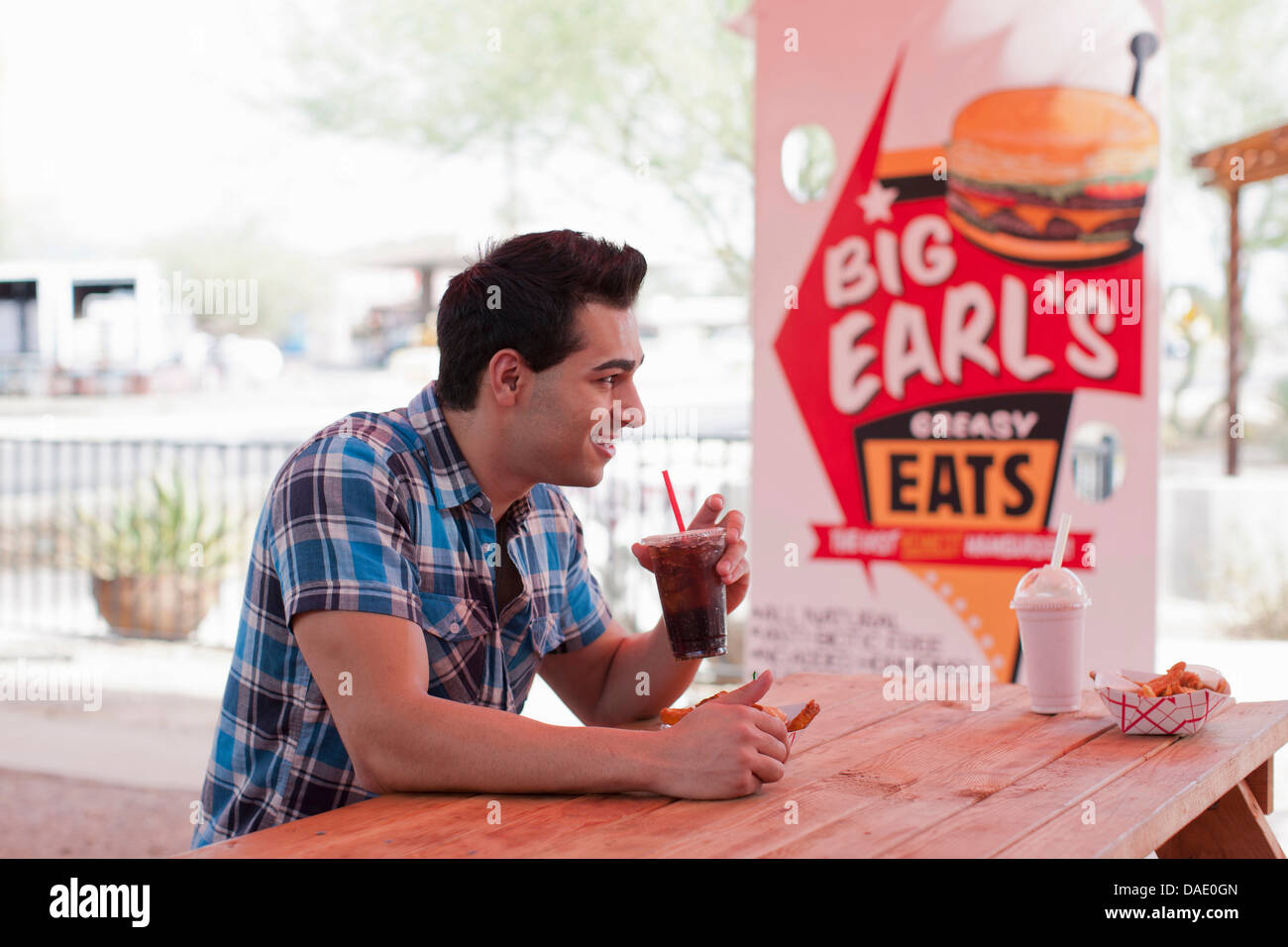 Young man drinking cola in diner, smiling Stock Photo