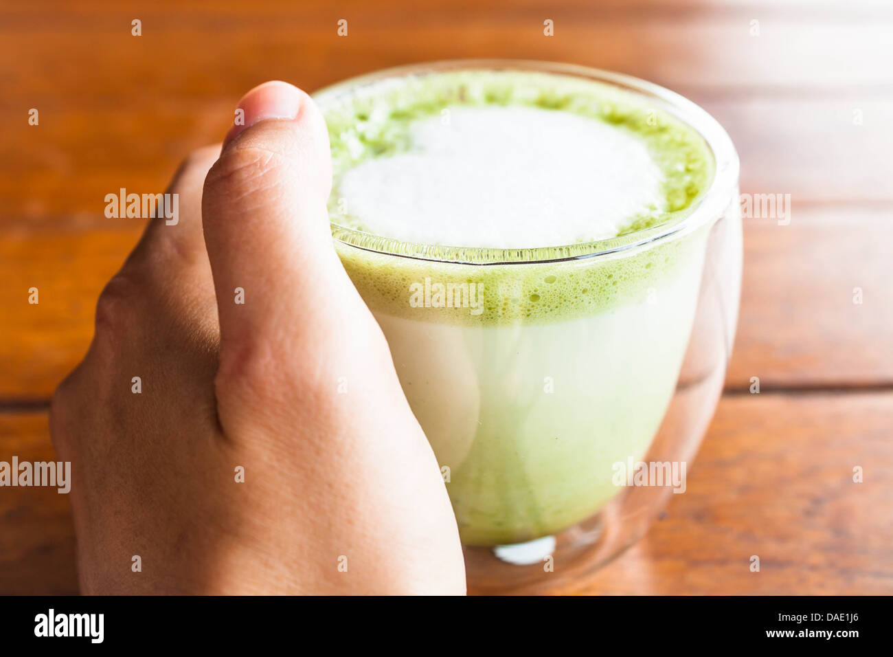 Hand on hot matcha green tea latte glass Stock Photo