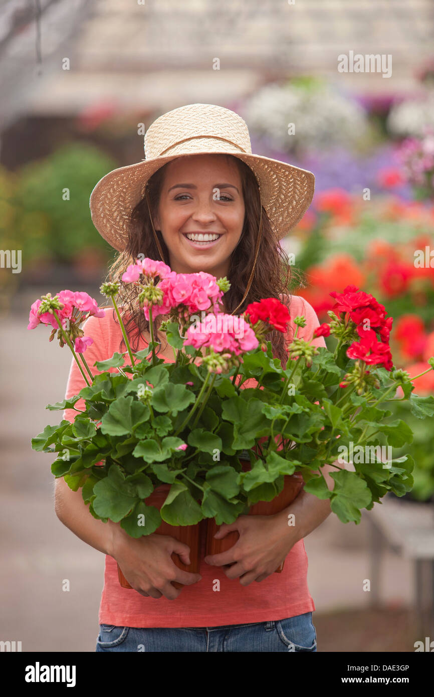 Young woman holding plants in garden centre, portrait Stock Photo - Alamy