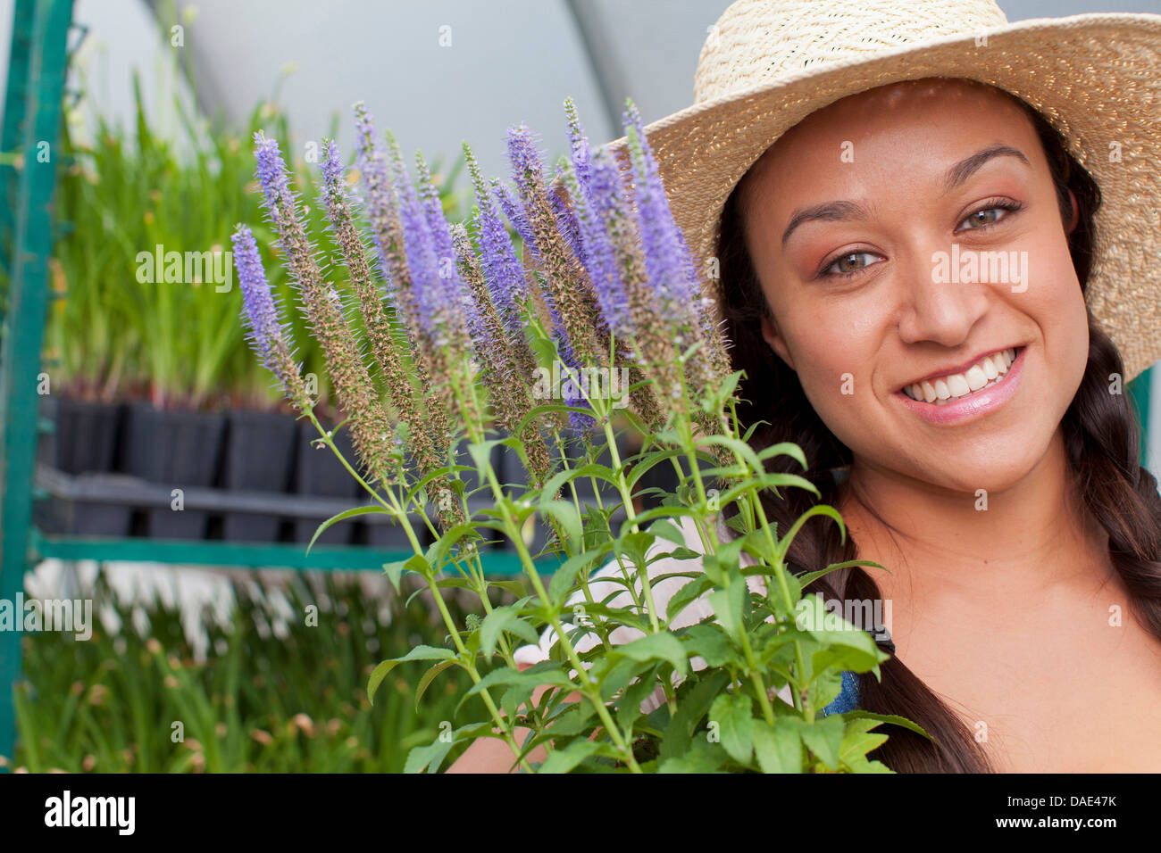 Young woman holding flowers in garden centre, portrait Stock Photo - Alamy