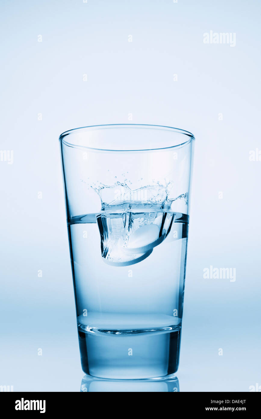 Tablets falling in glass of water Stock Photo