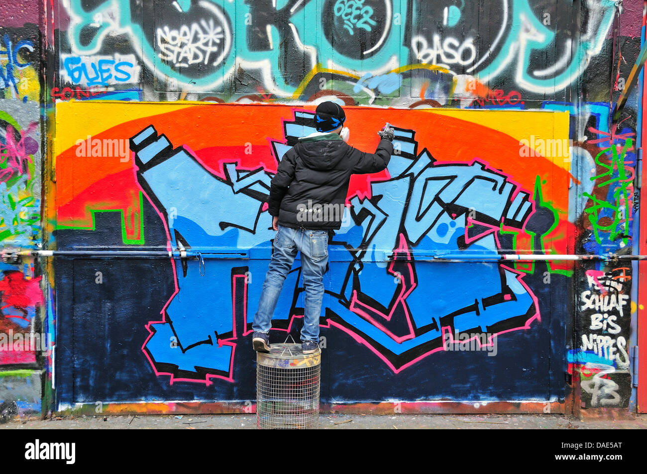 elevenyearold boy spraying at graffiti wall, Germany, North Rhine