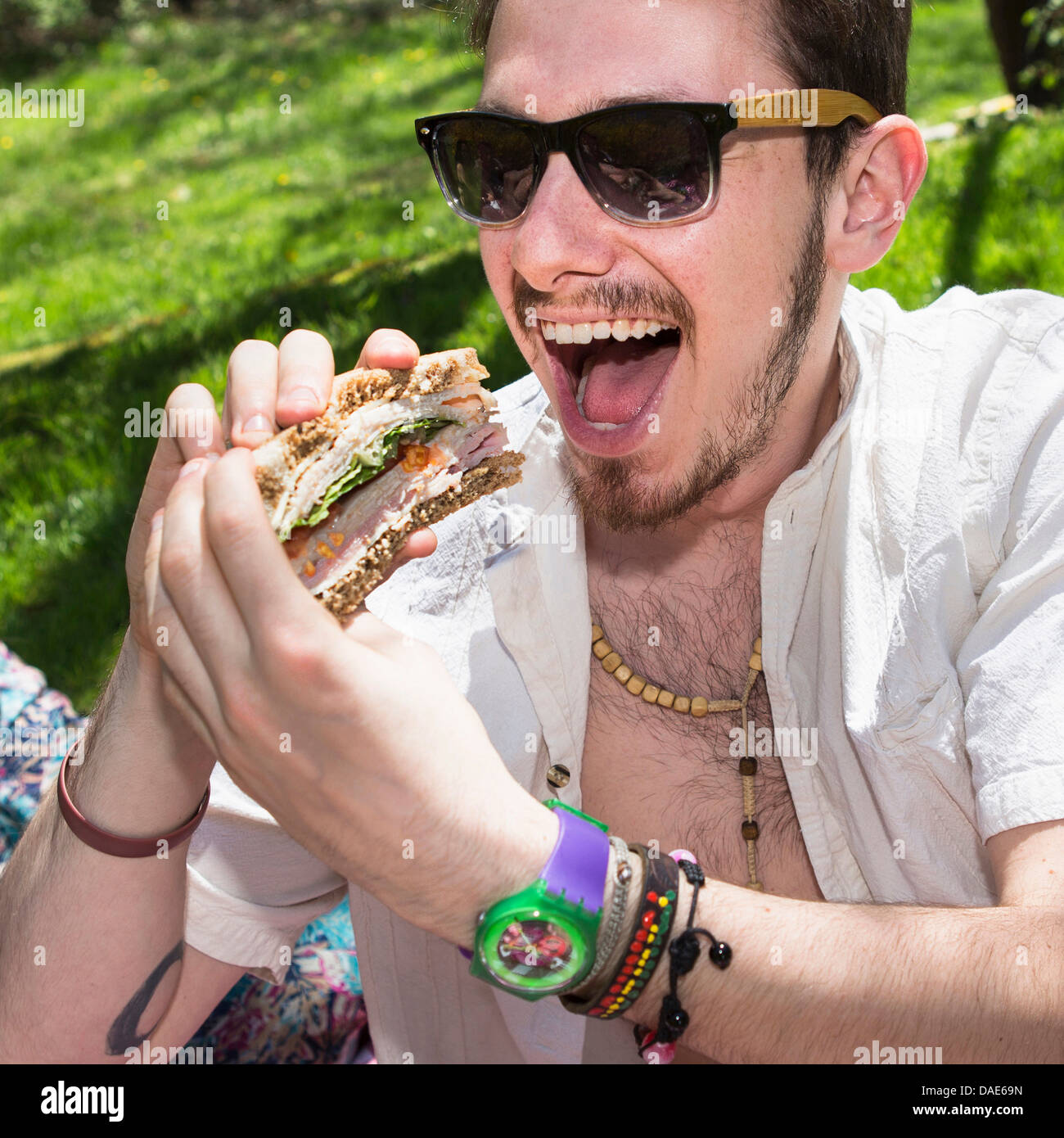 Man wearing sunglasses eating sandwich Stock Photo