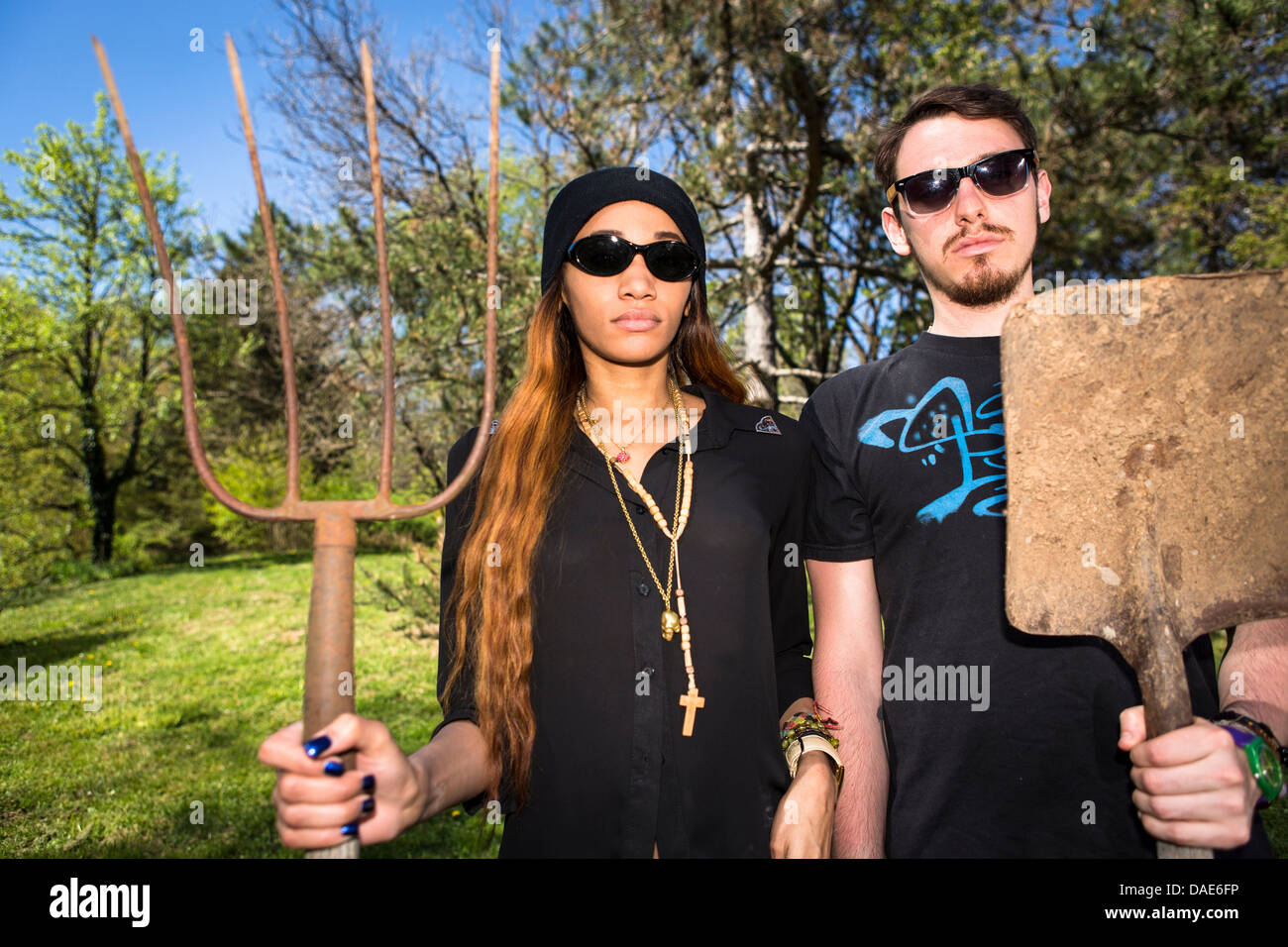 Couple holding pitchfork and spade, portrait Stock Photo Alamy