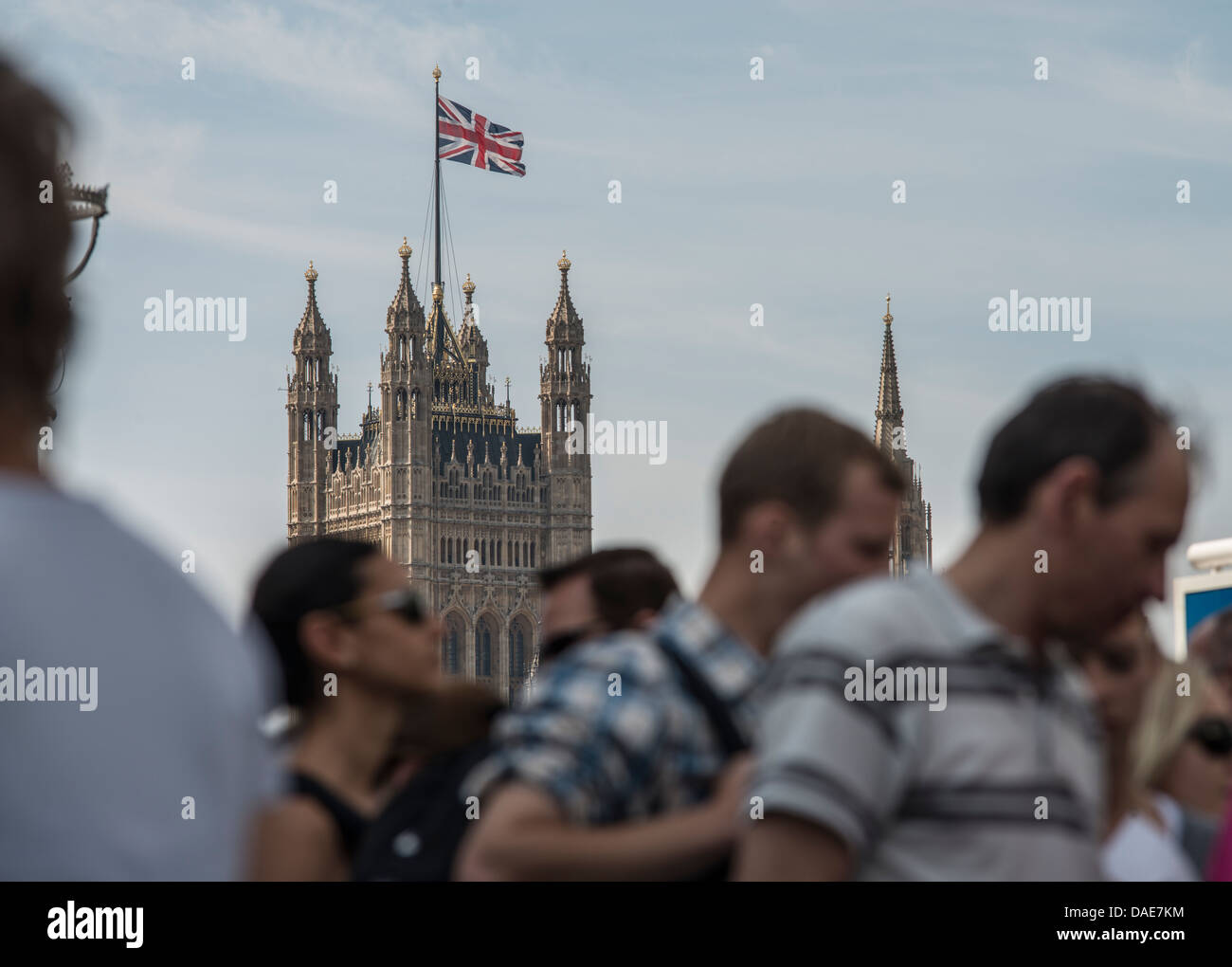 Olympic Games crowds walk along the Thames River in London as the Union Jack flies above The Victoria Tower on August 11, 2012. Stock Photo