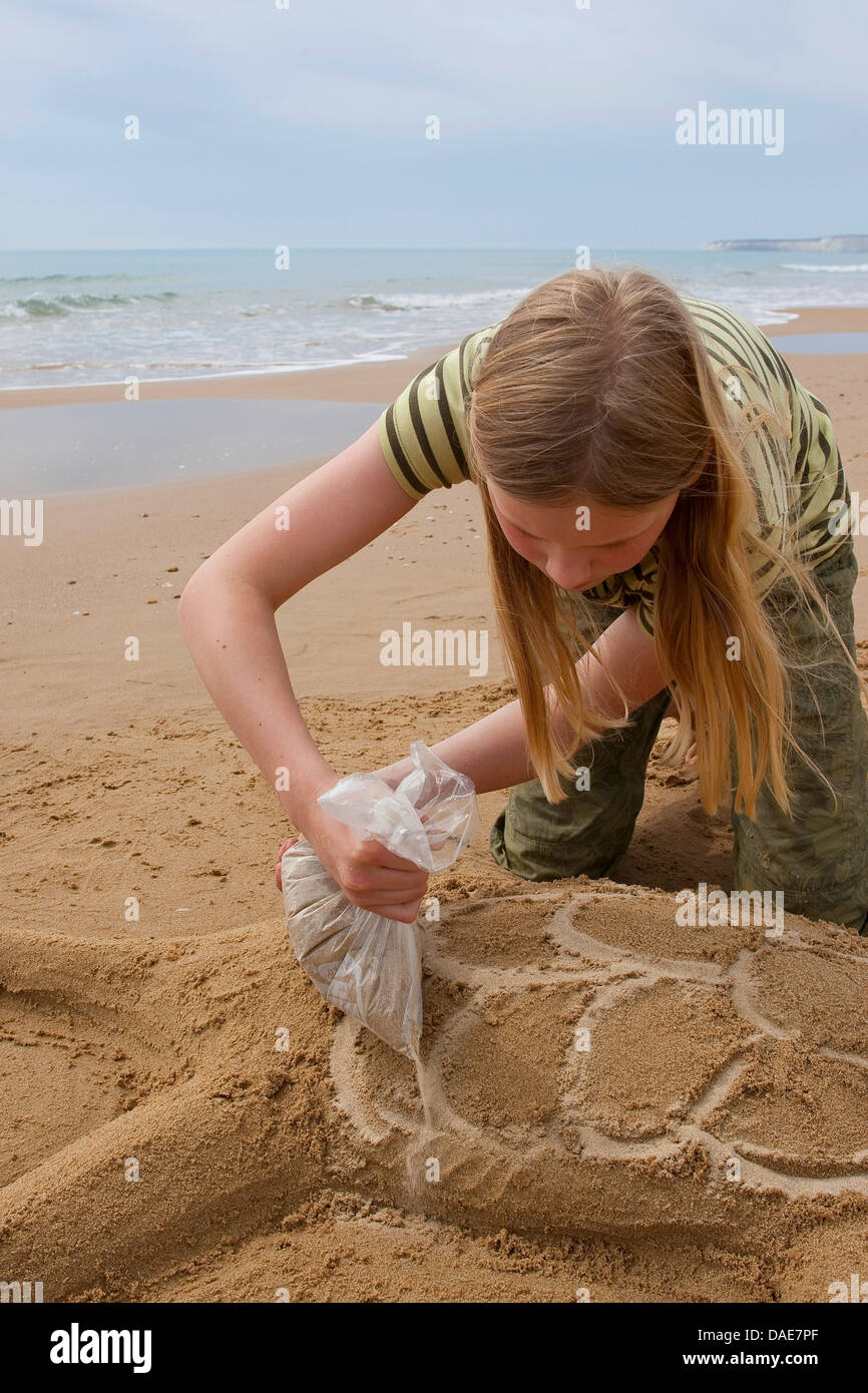 girl forming a sea turtle coming to shore for egg deposition at the beach in the sand, Italy, Sicilia Stock Photo