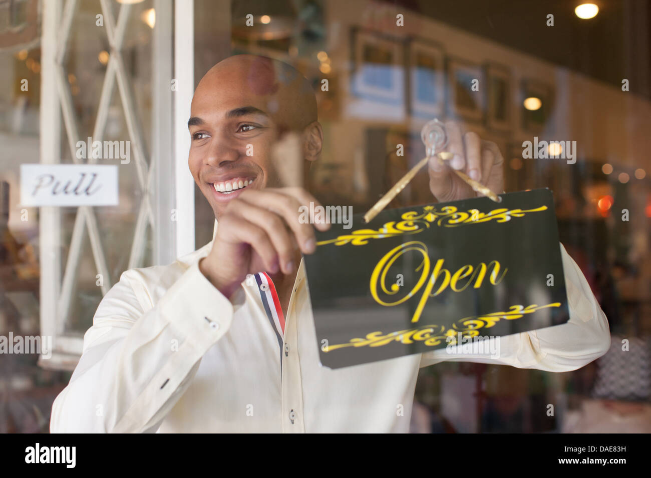 Shopkeeper turning open sign on vintage shop door Stock Photo