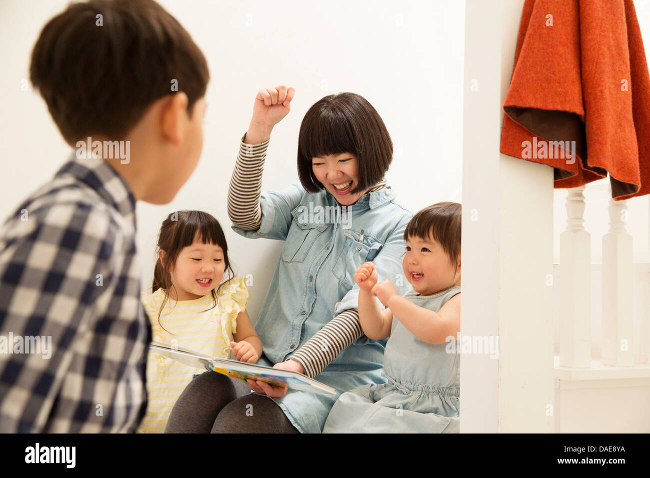 Mother and children laughing at storybook Stock Photo