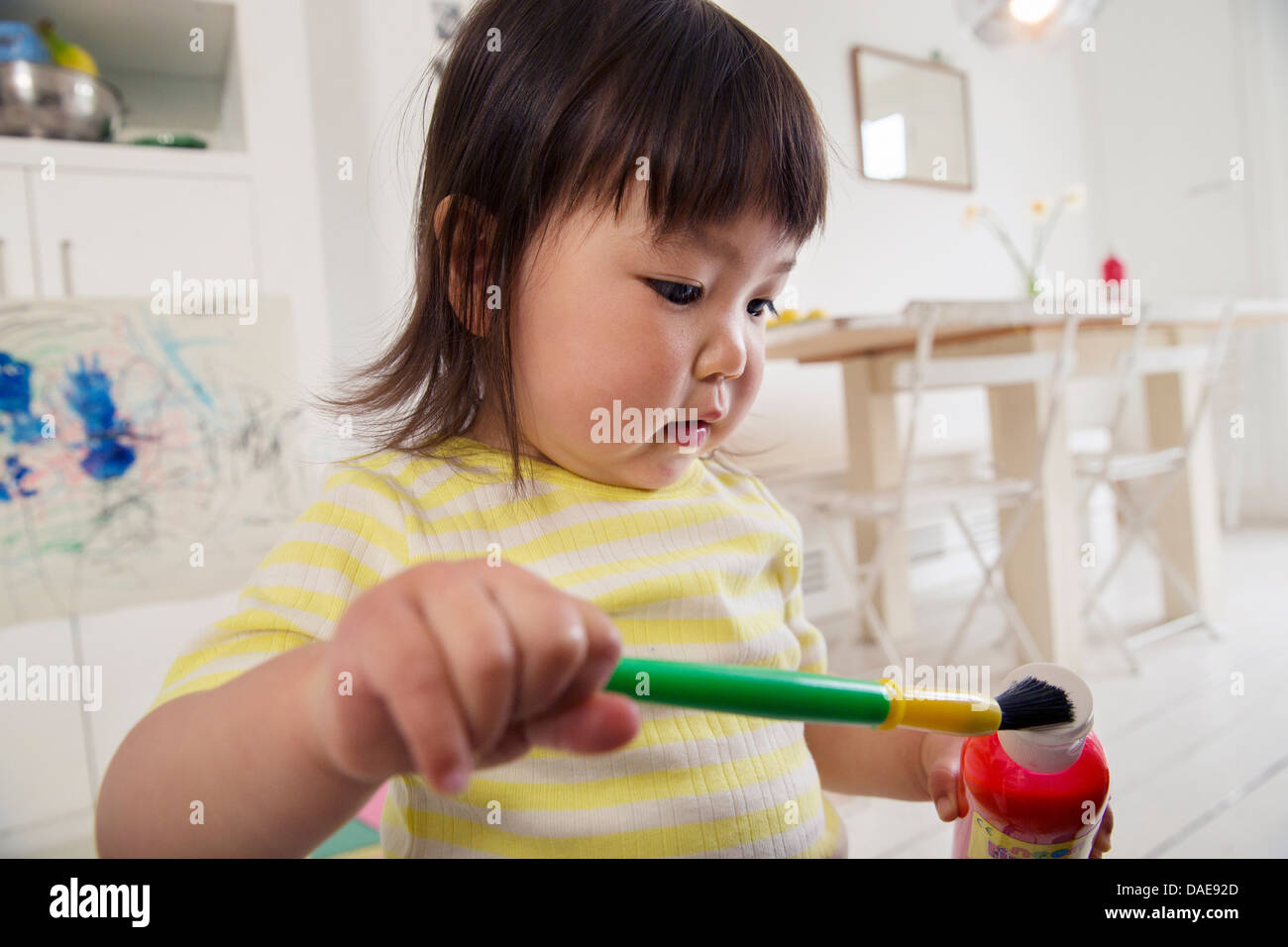 Female toddler holding paintbrush and paint Stock Photo Alamy