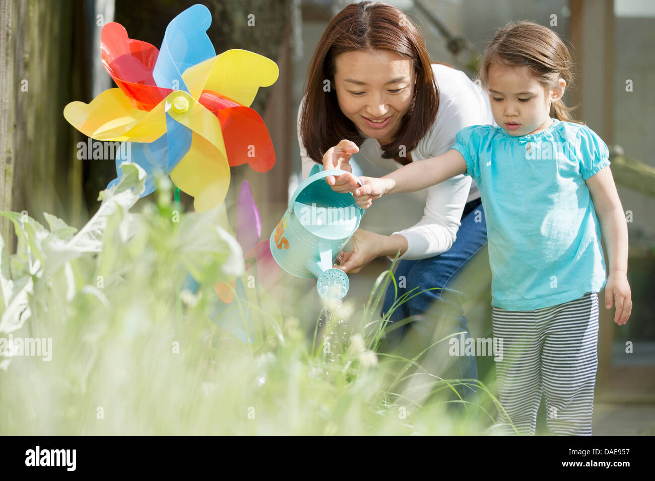 Mother and daughter with watering can and toy windmill Stock Photo