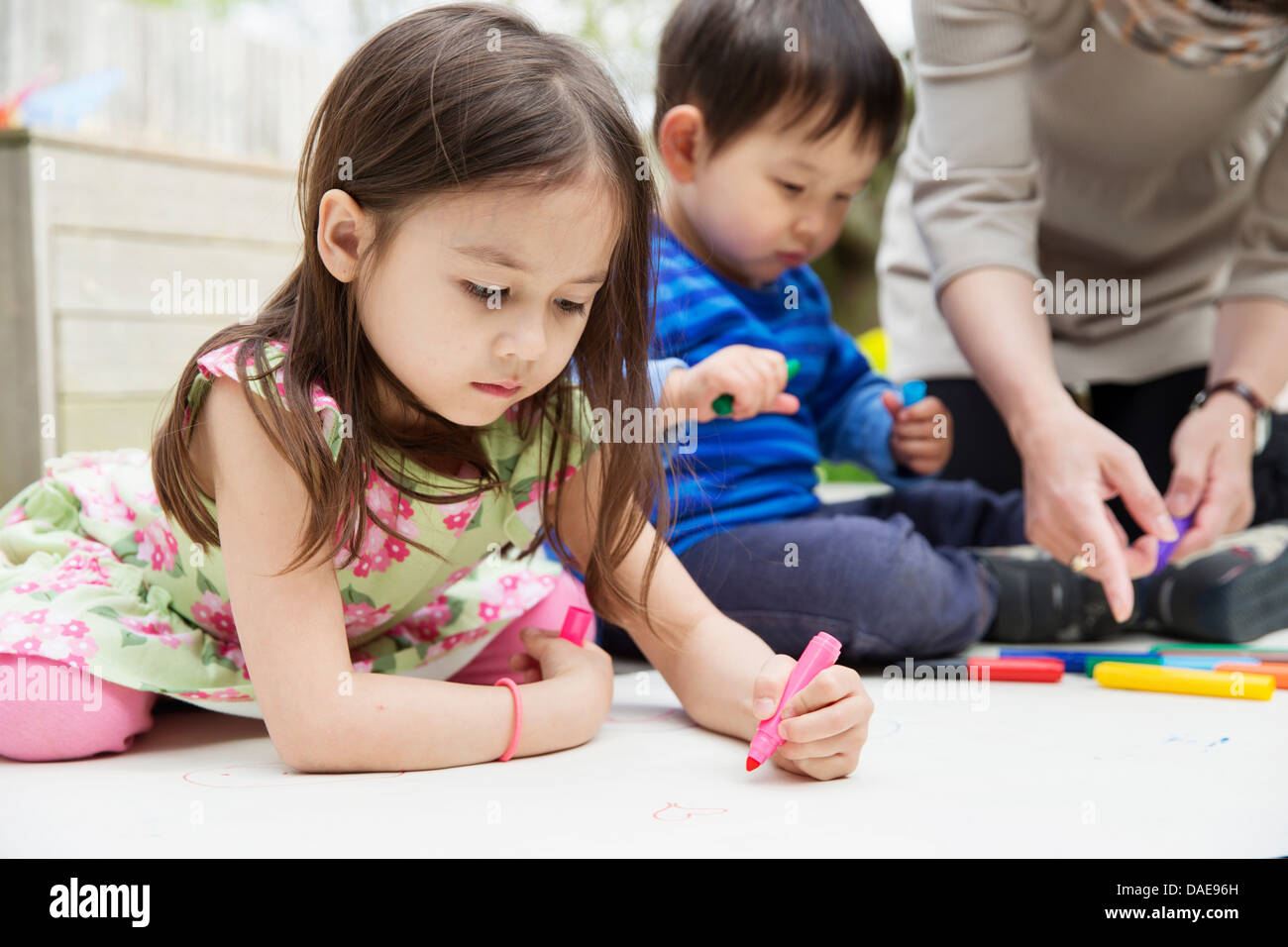 Mother and two children drawing in garden Stock Photo