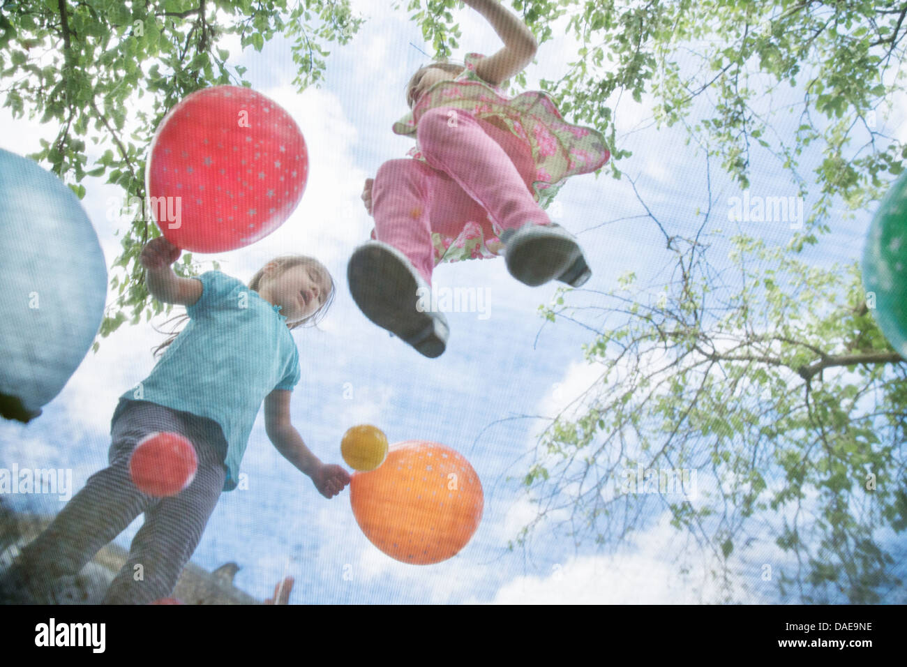 Young girls jumping on garden trampoline with balloons Stock Photo