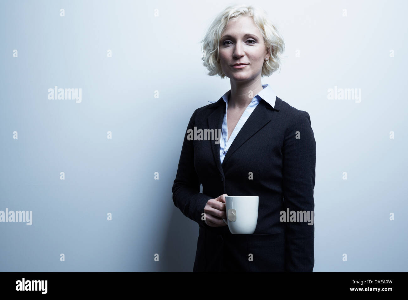 Studio portrait of blond businesswoman holding mug of tea Stock Photo