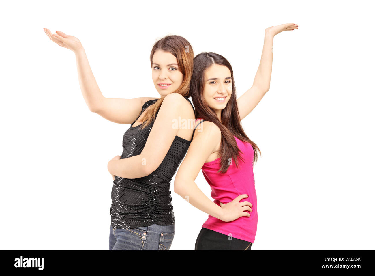 Happy girlfriends standing close together and gesturing with their hands Stock Photo