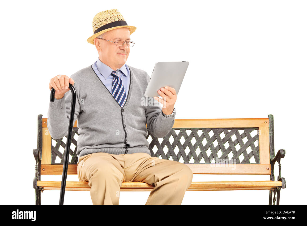 Senior man sitting on a wooden bench and reading from a tablet Stock ...