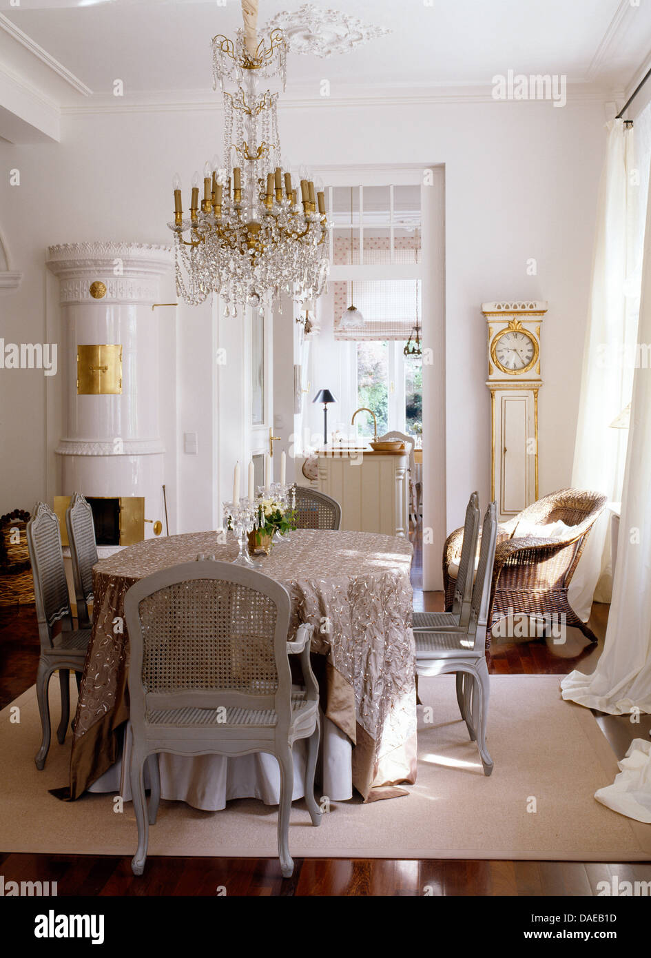 Ornate Glass Chandelier Above Table With Neutral Cloth And Gray Painted Chairs In German Dining Room White Ceramic Stove Ornate Glass Chandelier Above Table With Neutral Cloth And Gray Painted Chairs In German Dining Room White Ceramic Stove