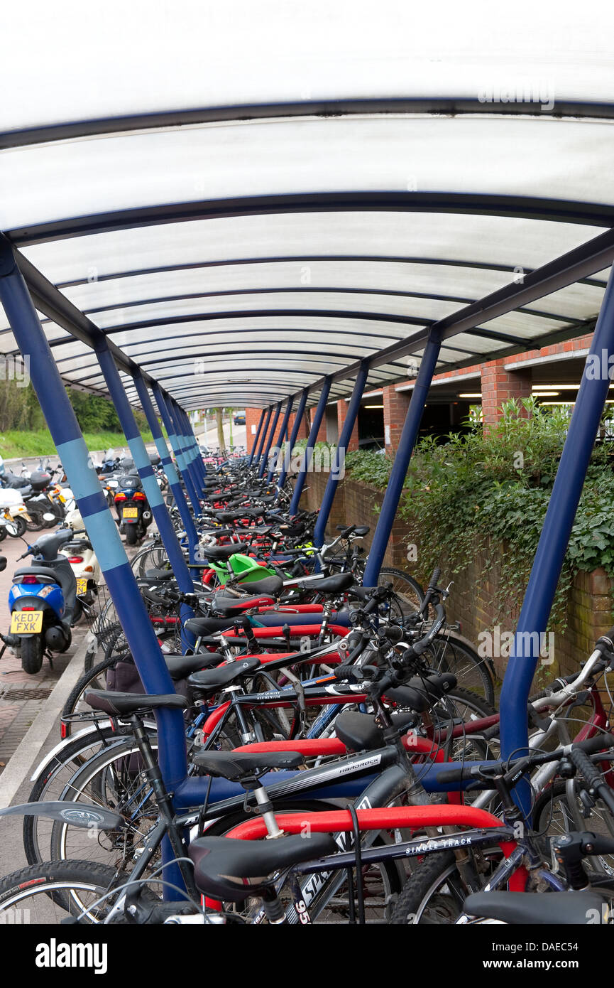 Bicycles parked securely undercover in a parking area outside a railway station in England. Stock Photo