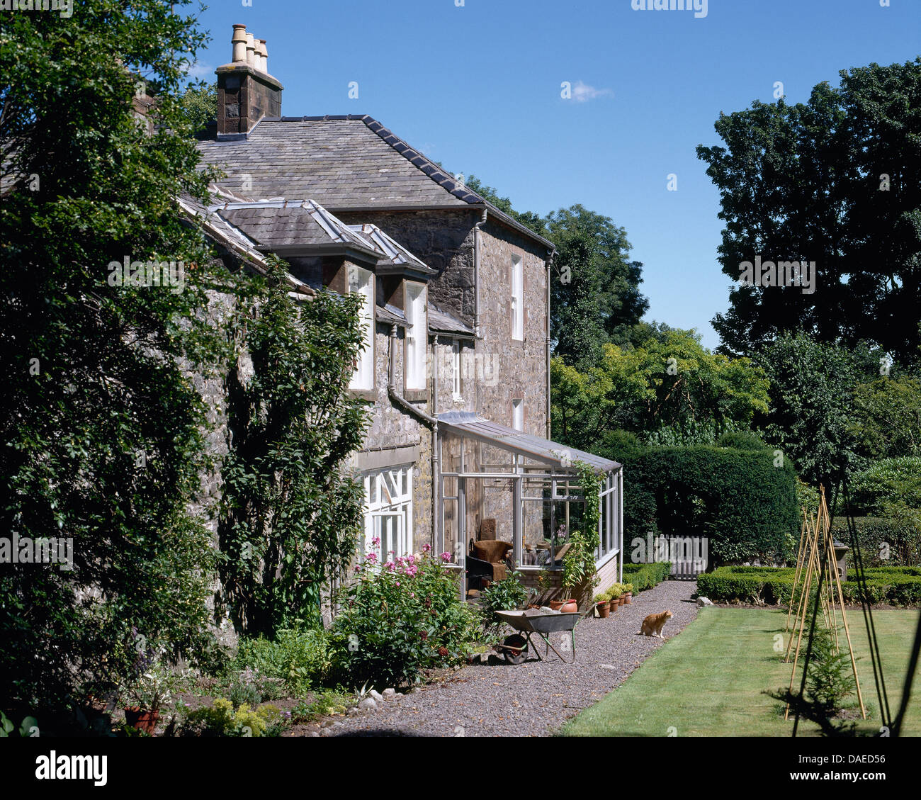 Exterior of stone country manor house with gravel path between house and newly mown lawn Stock Photo