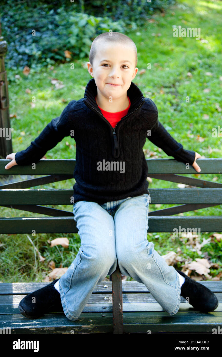 Smiling Boy Sitting on Park Bench Arm Rest Stock Photo - Alamy
