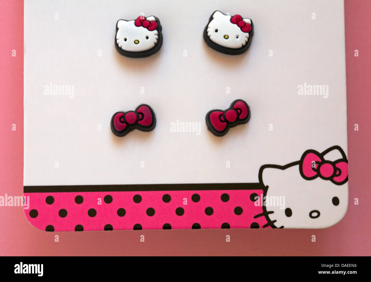 Hello Kitty earrings with bows set on pink background Stock Photo - Alamy