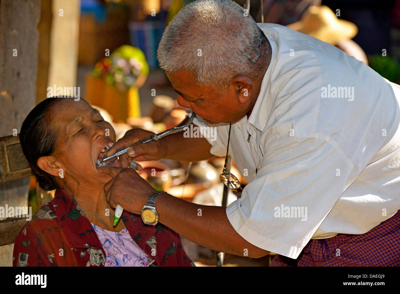 dentist attending an old woman at the market, Burma, Nam Pan Stock Photo
