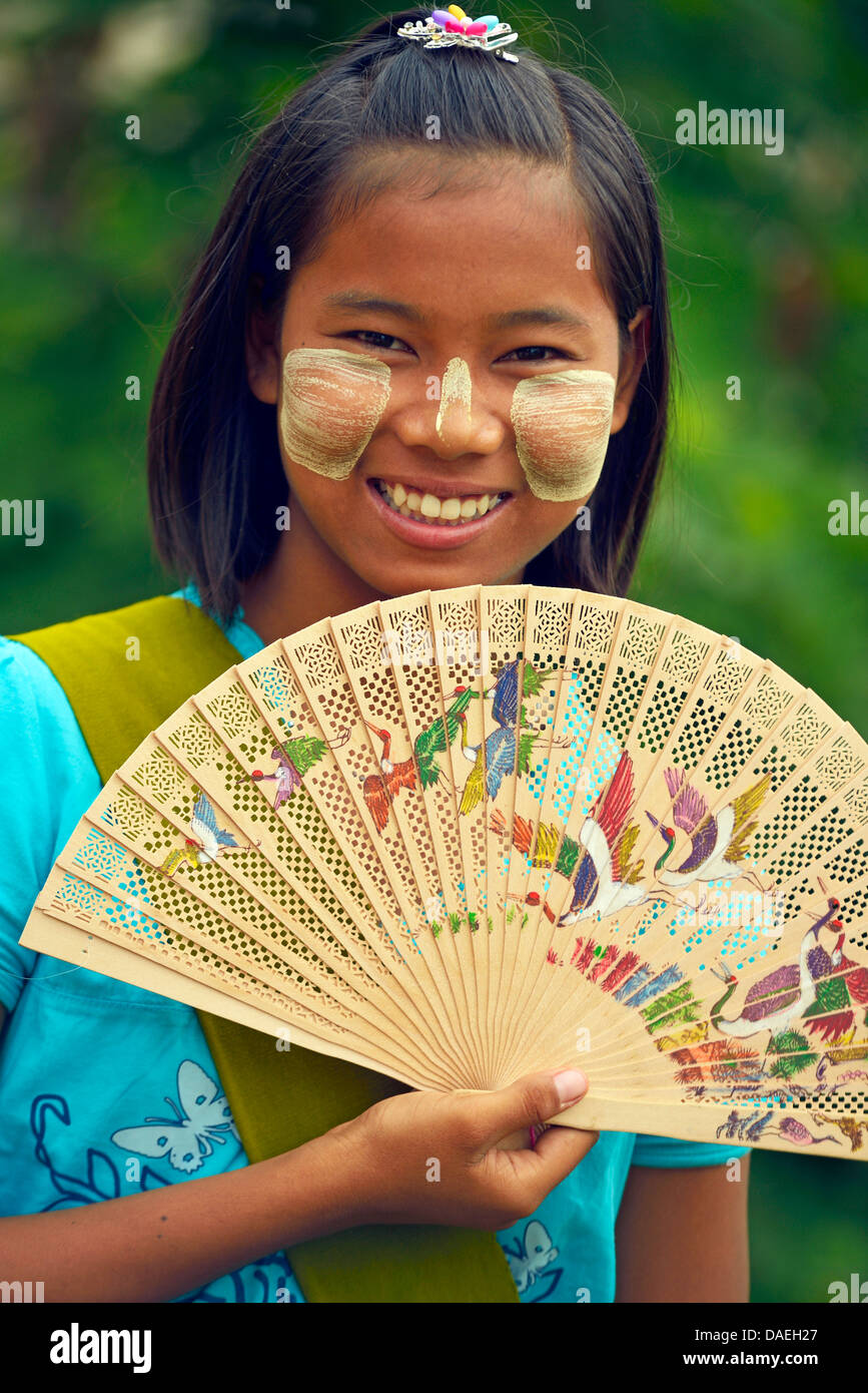 portrait of a young girl with fan made up with the traditional Burmese thanaka, a sun protection paste made of the thanaka tree, Burma, Mandalay Stock Photo