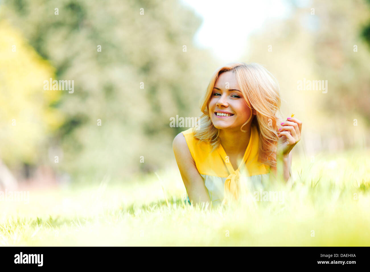 Happy young woman lying on grass Stock Photo - Alamy