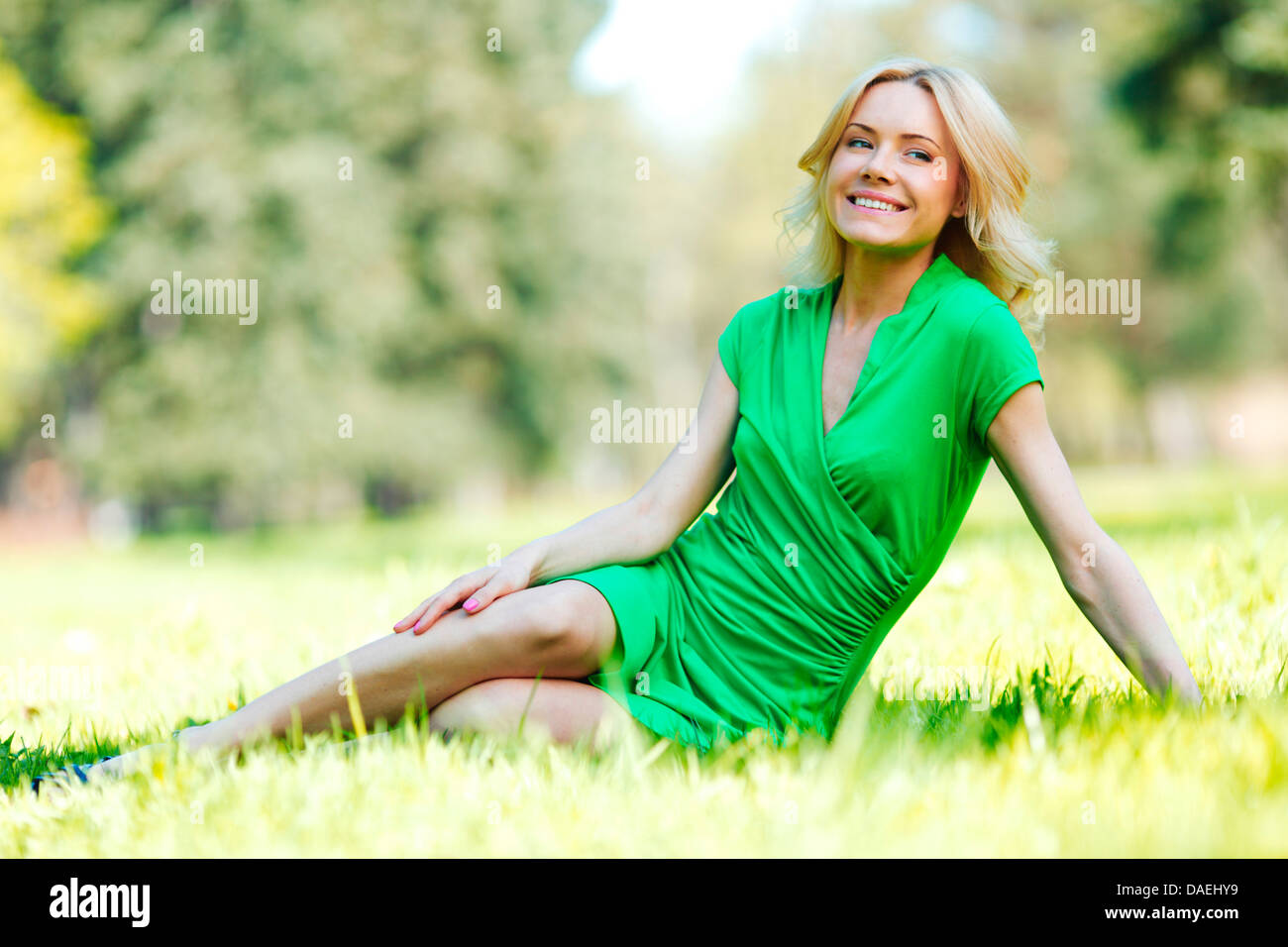 Happy young woman sitting on grass Stock Photo - Alamy